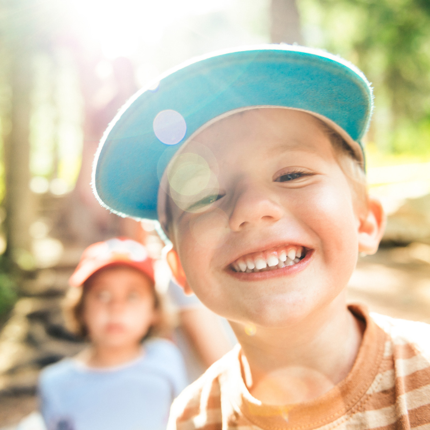 Young boy in the forest wearing a hat smiling