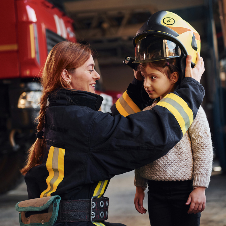 Fire fighter placing helmet on child's head