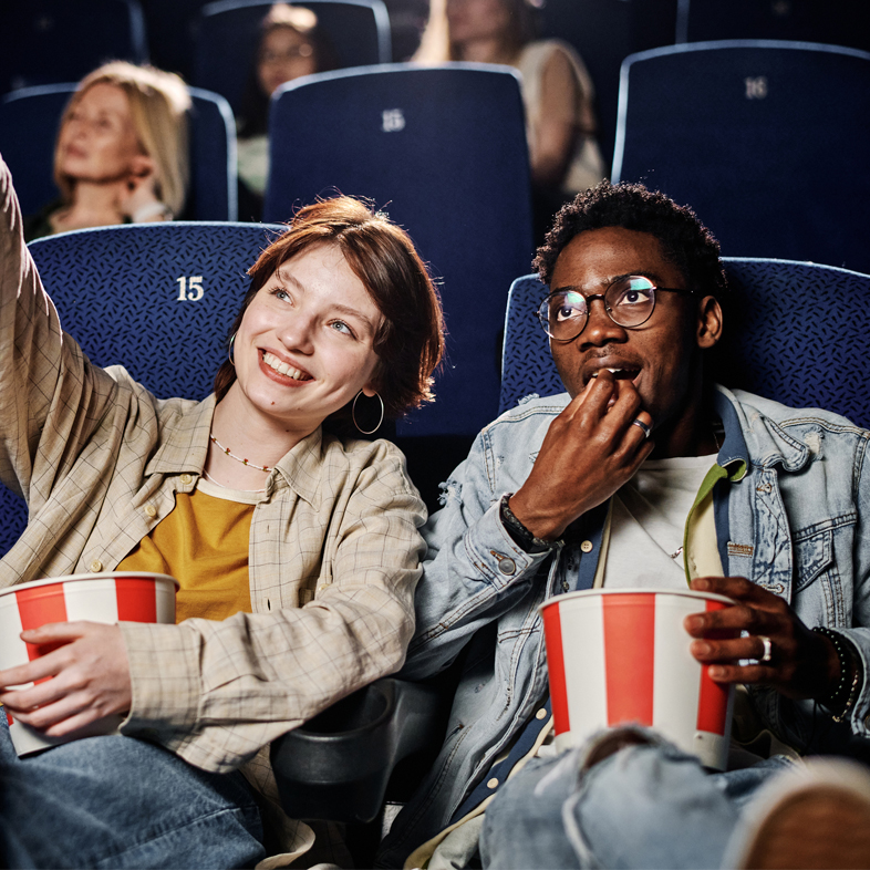 Two teens watching a movie in the theater
