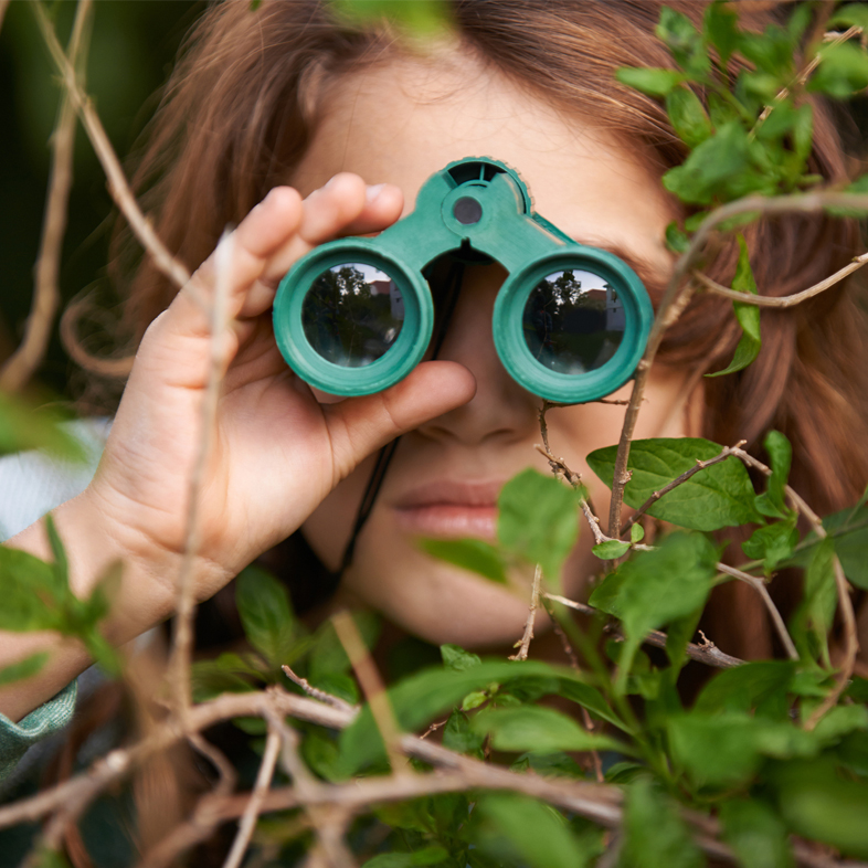 Child in bushes with binoculars