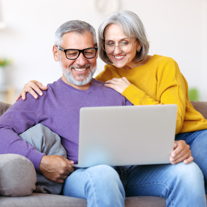 Senior couple smiling and looking at laptop