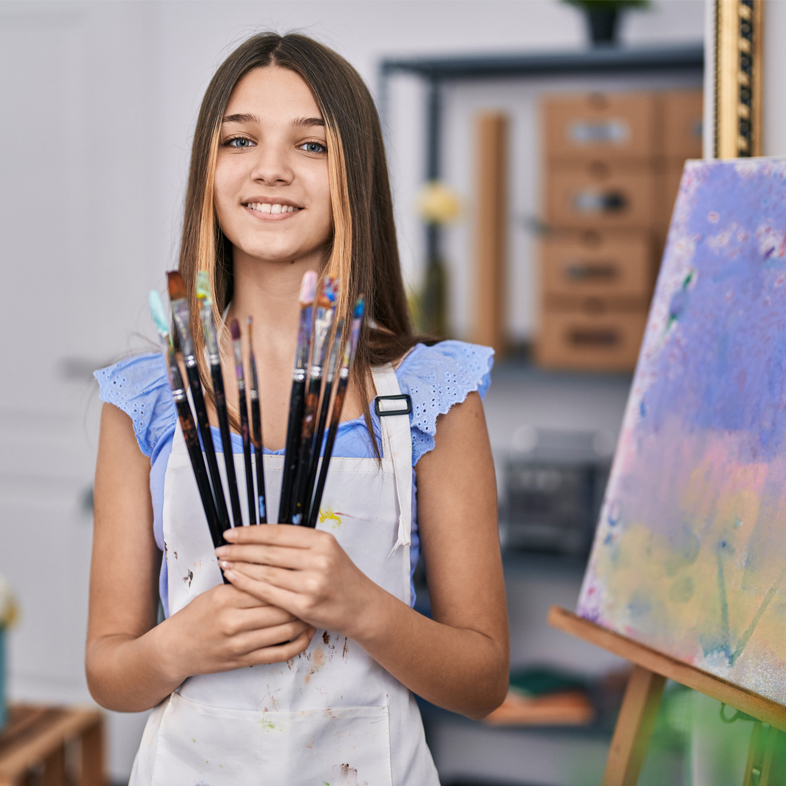 Teen girl holding paint brushes