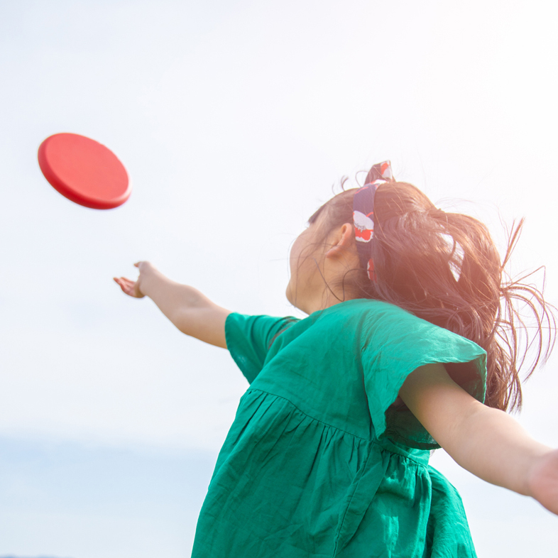 Young girl throwing frisbee in air