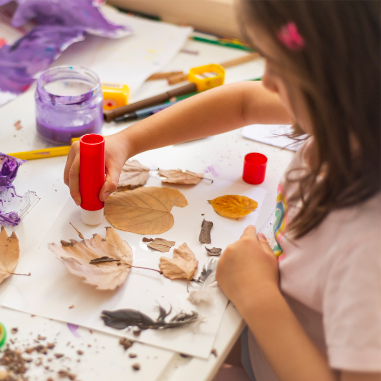Preschool girl participating in a craft with leaves