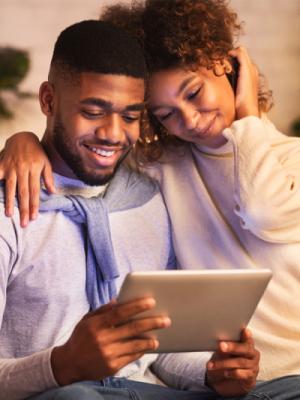 Couple cuddling looking at tablet