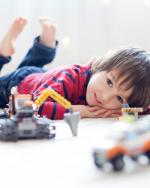 Child laying on floor with lego vehicles