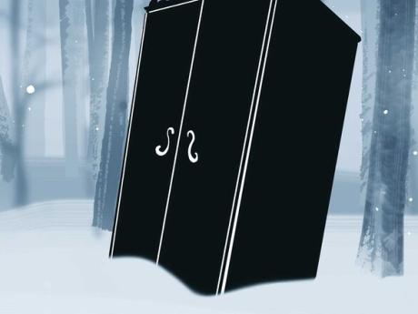 A black wardrobe sits partially buried in the snow. Thin trees can be seen behind it, half shrouded in mist. 