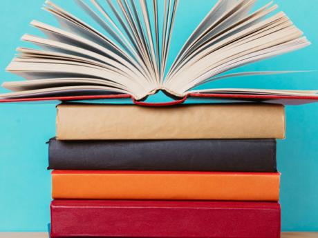 Colorful book stack on a blue background with an open book on top