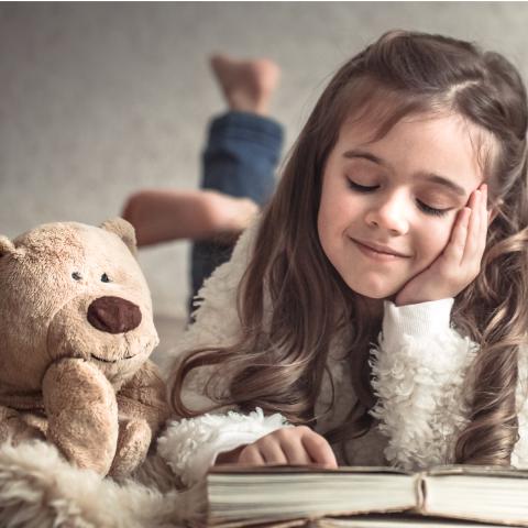 Child reading with Teddy Bear