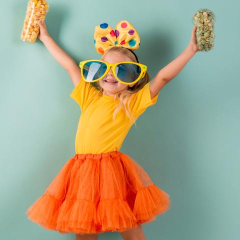 Child wearing bow and sunglasses holding popcorn
