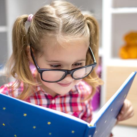 Preschooler in glasses reading a book