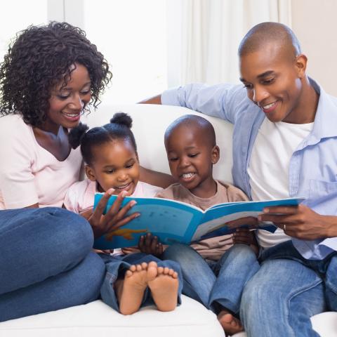 Family reading a book on the couch