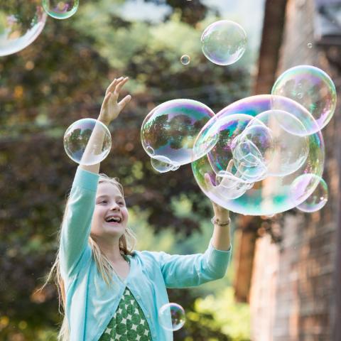 Child playing with bubbles outside