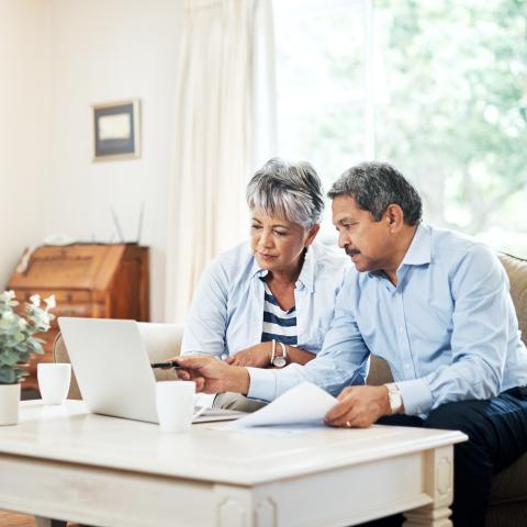 Senior couple looking at computer holding papers