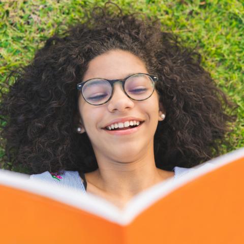 Teen reading book on grass