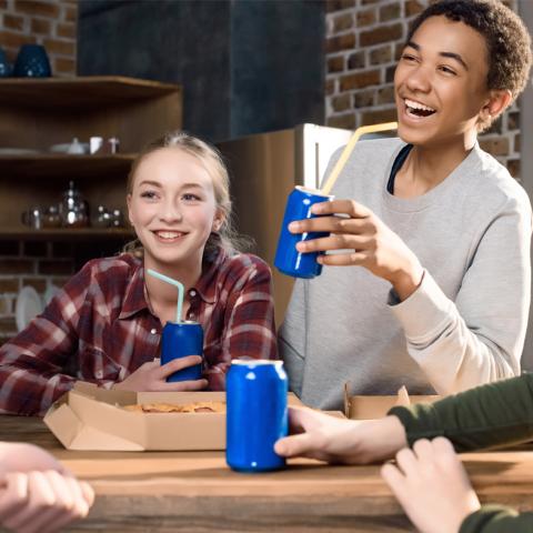 Teens eating pizza and drinking soda