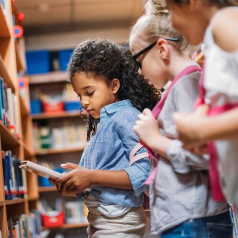 Girls reading book from shelf