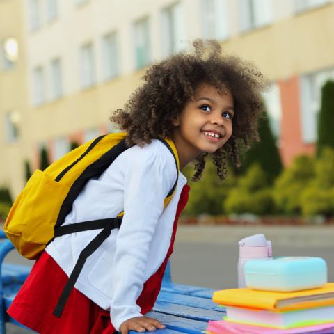 Preschool age girl wearing backpack and smiling