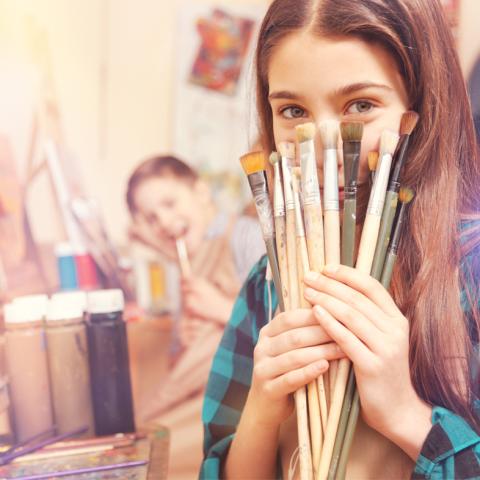 Teen girl holding paint brushes