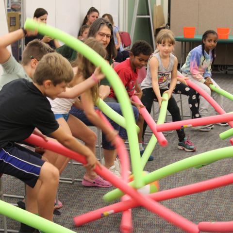 Children playing foosball with pool noodles