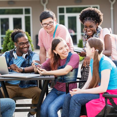 Teens sitting outside at a table talking