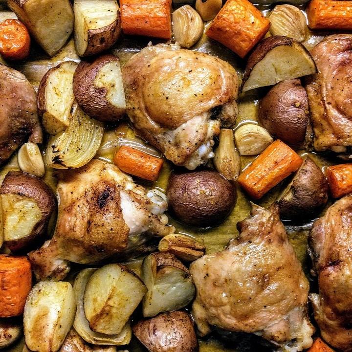 Chicken and vegetables roasting on a sheet pan