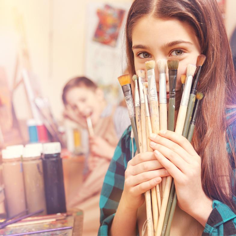 Teen girl holding paint brushes